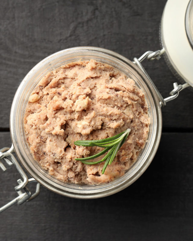 Glass jar of pate on wooden background